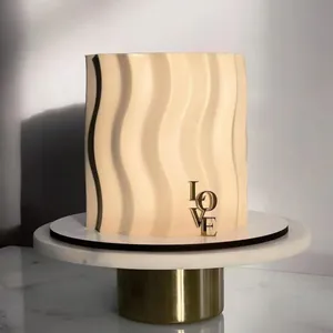 Détail du topper LOVE en acrylique doré sur un gâteau à la crème ondulé avec ombres douces