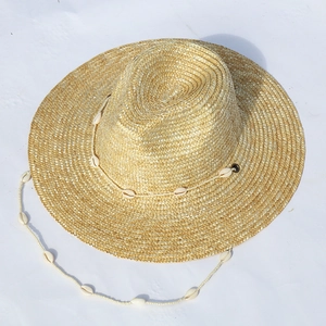 Dettaglio del cappello di paglia con catena di conchiglie su sfondo bianco