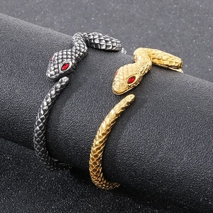Close-up of snake bracelets with red stone eyes and detailed scale texture in gold and silver