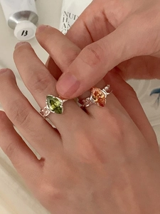 Close-up of 925 silver rings with marquise green and orange zircons on a model's hand