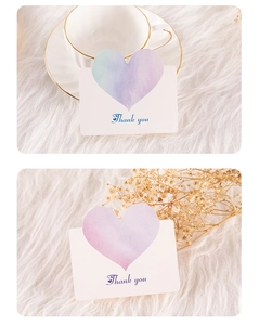 Detail of watercolor gradient thank you card with heart cutout on white plush surface