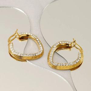 Golden heart earrings with crystals and Greek key pattern on mirrored circular backdrop