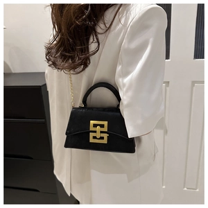 Detail of a chic black suede crossbody bag featuring a golden square lock and chain strap