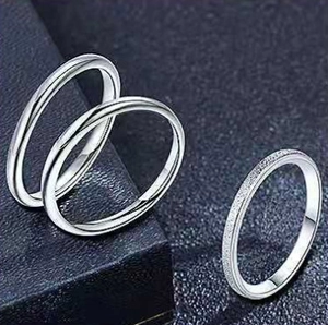 Close-up of three-piece silver titanium steel rings with smooth and frosted textures