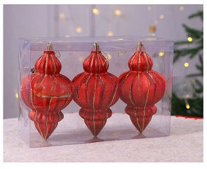Drei rote Weihnachtskugeln in Zwiebelform mit Goldglitzer in einer Geschenkbox