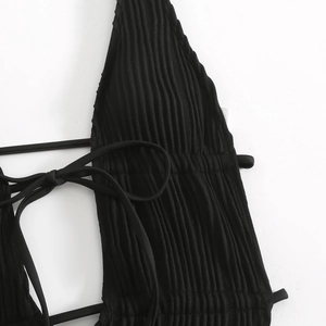 Dettaglio del tessuto a costine nere con trama verticale sul top bikini con lacci