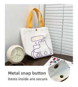 Detail view of the metal snap button closure on a cute cartoon canvas tote bag