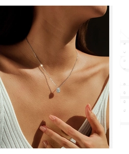 Detailed view of an oval moissanite pendant necklace on a neck with Good Luck text
