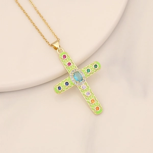 Detail of vintage gold cross pendant with green enamel and colorful inlaid gemstones