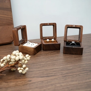 Macro detail of walnut wood jewelry box featuring clear glass lid and velvet ring slots
