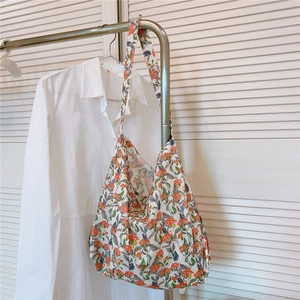 Détail du sac cabas en coton à fleurs orange avec une large bandoulière suspendue