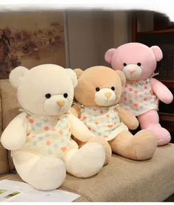 Détail de trois ours en peluche rose et marron, posés sur un canapé beige douillet