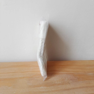 Detail of a folded white knitted Christmas stocking packed in a clear protective plastic bag