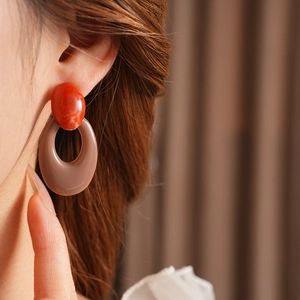 Close-up of vintage resin oval hoop earrings with red agate texture on a model