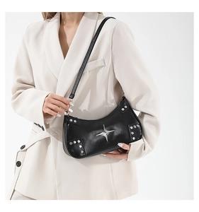 Detail view of black crescent shoulder bag with metallic star and rivet decorations