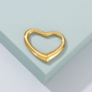 Minimalist gold heart pendant made of titanium steel on a light blue geometric pedestal