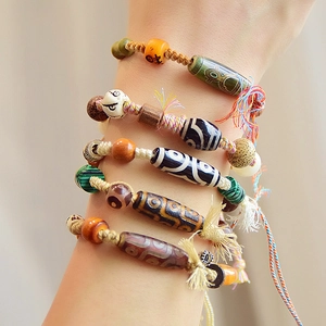 Retro ethnic Dzi agate bead bracelets with colorful tassels worn by a model
