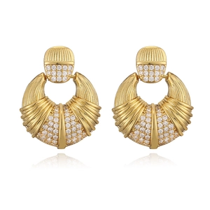 Macro view of gold fan-shaped earrings featuring pave-set crystals and ribbed metal textures