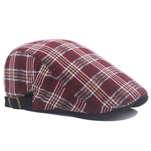 Detail of red plaid newsboy cap showing adjustable strap and vintage metal buckle