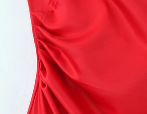 Detail of red satin mermaid dress fabric with smooth texture and shiny folds