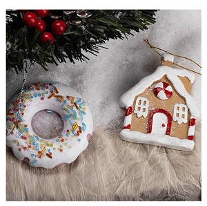 Close-up of resin snowflake donut and gingerbread house Christmas ornaments with snow accents