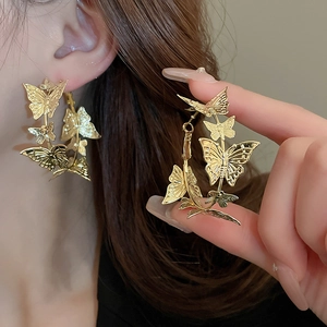 Detailed view of oversized gold butterfly earrings with intricate hollow wing textures