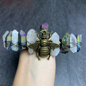 Macro shot of natural crystal crown with brass bee badge and wire wrapping details