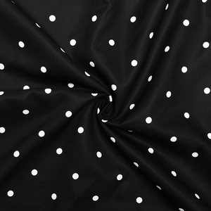 Vue macro d'un tissu vintage à pois blancs sur fond noir avec des plis soyeux