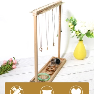 Detail of wooden jewelry stand with metal hooks and base tray for necklaces and bracelets
