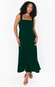 Detail of dark green square neck sleeveless dress featuring a flowing ruffled hemline