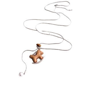 Silver snake chain necklace with wooden horse pendant and white pearl accent on white background