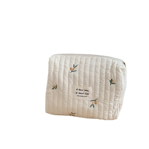 Off-white quilted baby stroller organizer bag with olive branch embroidery and top handle