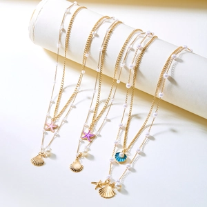 Layered gold necklaces with colorful starfish, shells and pearls on a white display