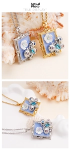 Detailed close-up of Monet style butterfly and flower pendant necklace on a seashell