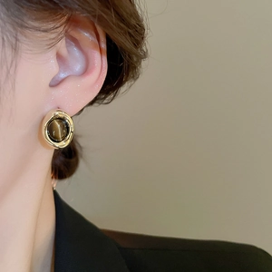 Macro view of vintage gold-plated earrings with tiger eye stone on a model's ear