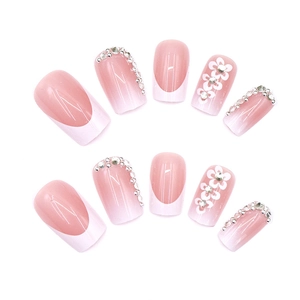 Pink and white gradient press-on nails with 3D flower charms and rhinestones