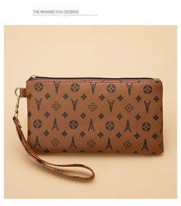 Detail of vintage brown PU leather clutch bag with monogram pattern and gold zipper strap