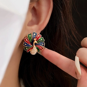Detailed view of vintage peacock-shaped earrings with colorful enamel and faux pearls