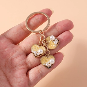 Detail of gold keychain with yellow marble enamel hearts and white faux pearls
