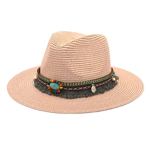 Detail of light pink woven straw fedora featuring bohemian ethnic beadwork and tassels