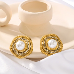 Twisted gold earrings with pearls and zircons on white silk and ceramic background
