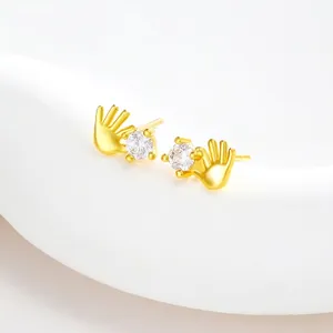 Detailed macro view of 24k gold-plated hand-shaped earrings with round zircon stones