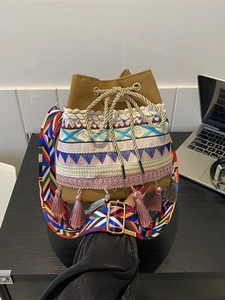 Bohemian bucket bag with colorful embroidery and tassel detail on brown canvas material