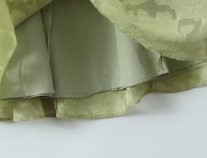Nahaufnahme vom grasgrünen Kleidsaum mit strukturiertem Jacquard-Stoff und Futter