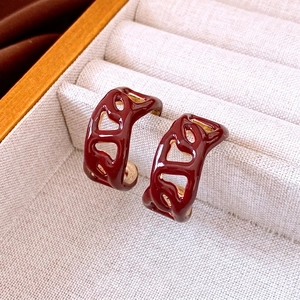 Elegant 18K gold-plated wine red enamel hollow wavy hoop earrings for women on display