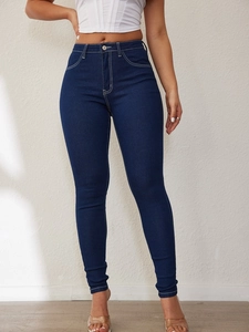 Detail of high waisted skinny jeans in dark blue with contrast white stitching