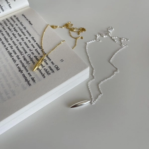 Minimalist 925 sterling silver necklaces in gold and silver teardrop pendants on a book