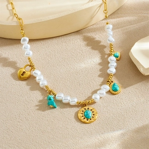 Golden necklace with pearls, heart lock pendant and turquoise charms on beige surface