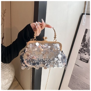 Silver sequin evening bag with gold carved metal handle and chain strap held by hand