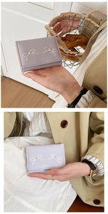 Close-up of a purple bow wallet with pearls held by a model in a beige coat